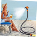 Standing patio misting hose with orange 360° nozzle, spraying fine water mist from loop