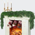 Green artificial pine garland with dense layered needle tips, draped in a straight row.