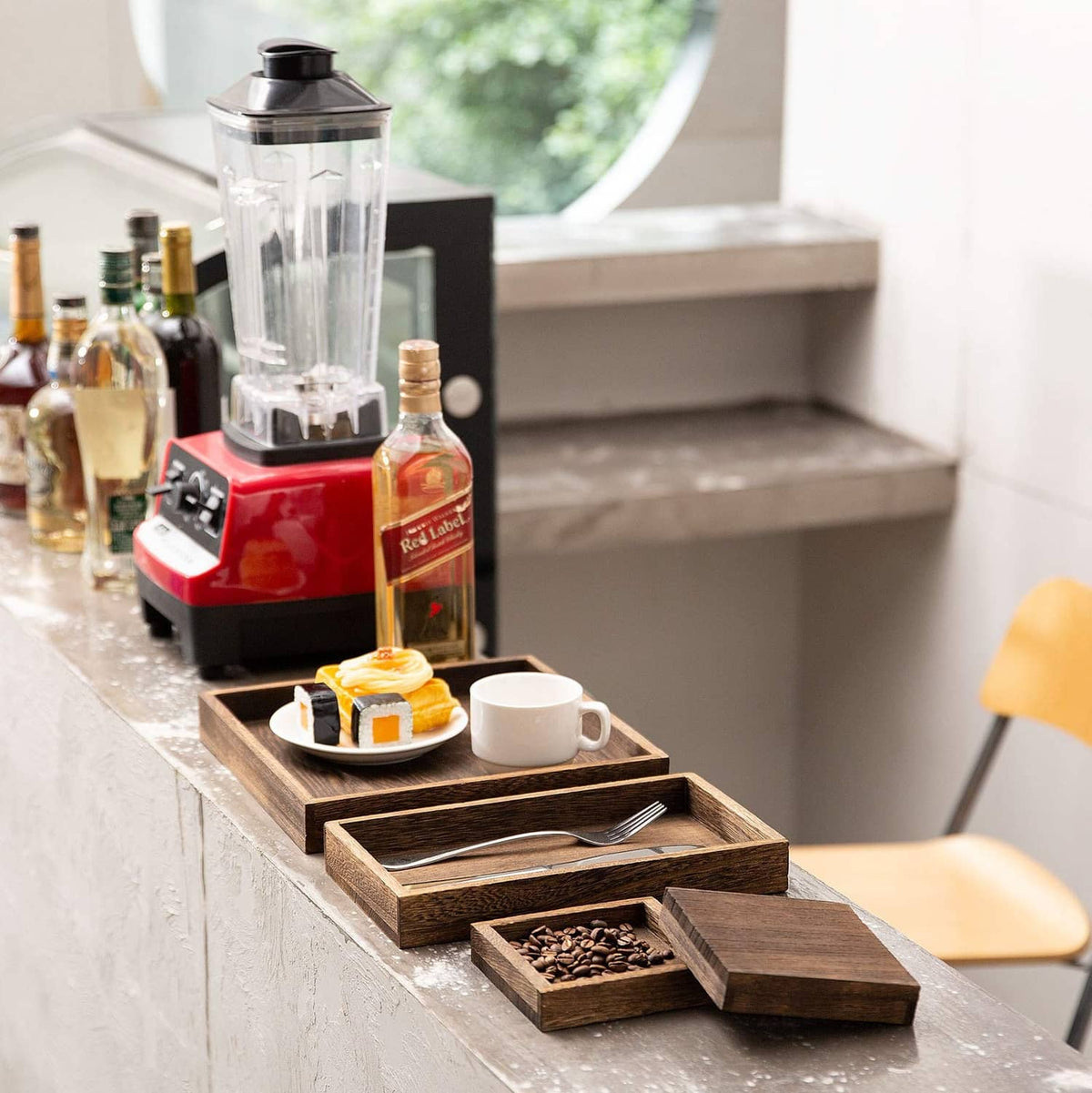 Rustic wooden serving tray with handle slots holding cups, bottles, and utensils