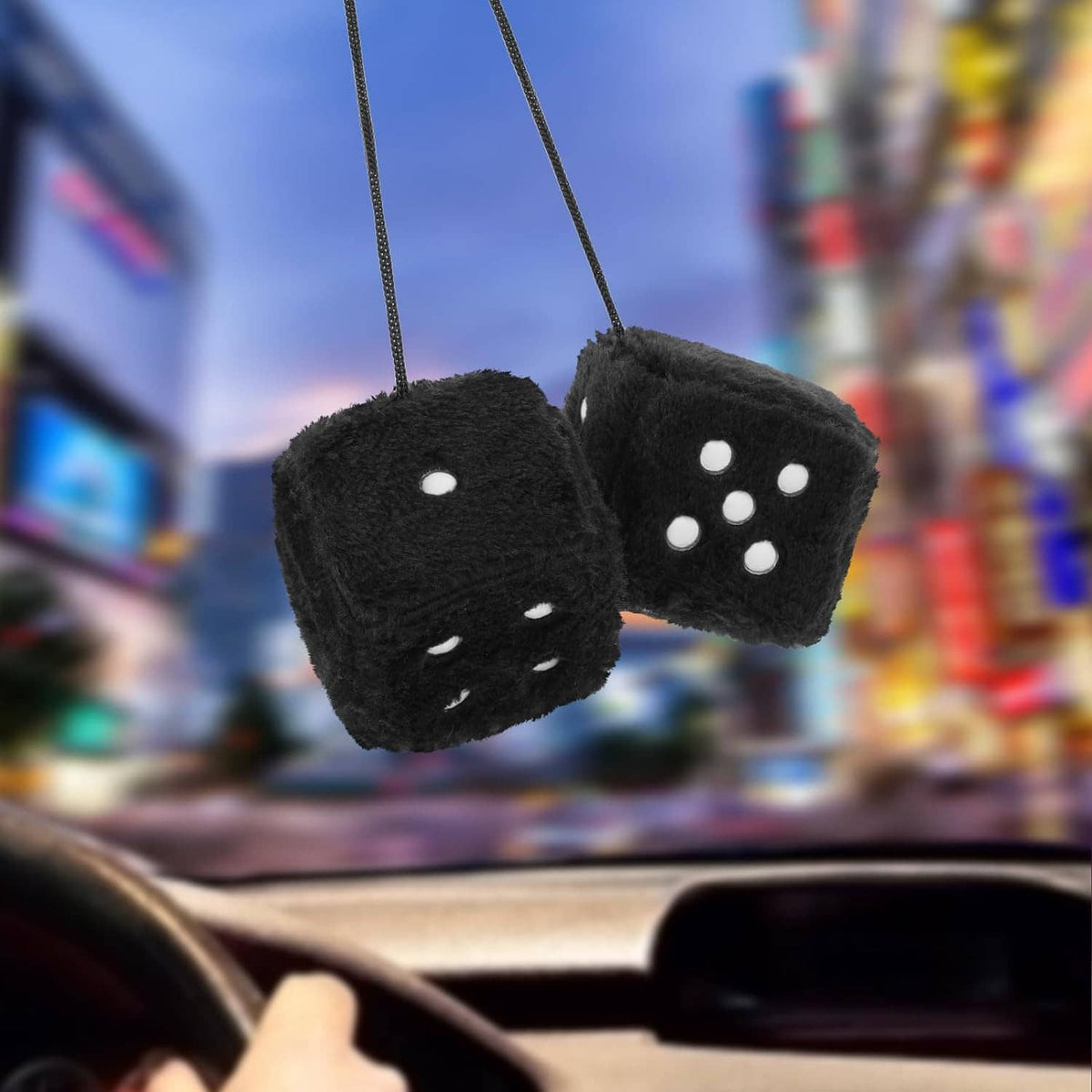 Pair of black fuzzy dice with white dot faces, hanging from rear-view mirror
