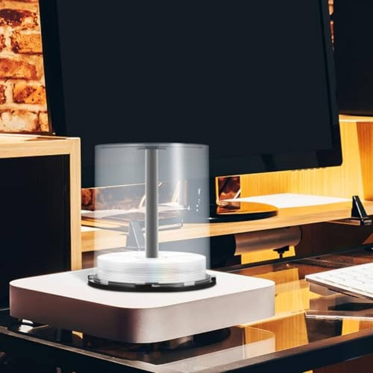 Clear CD/DVD spindle storage case on desk with central hub and dark base ring