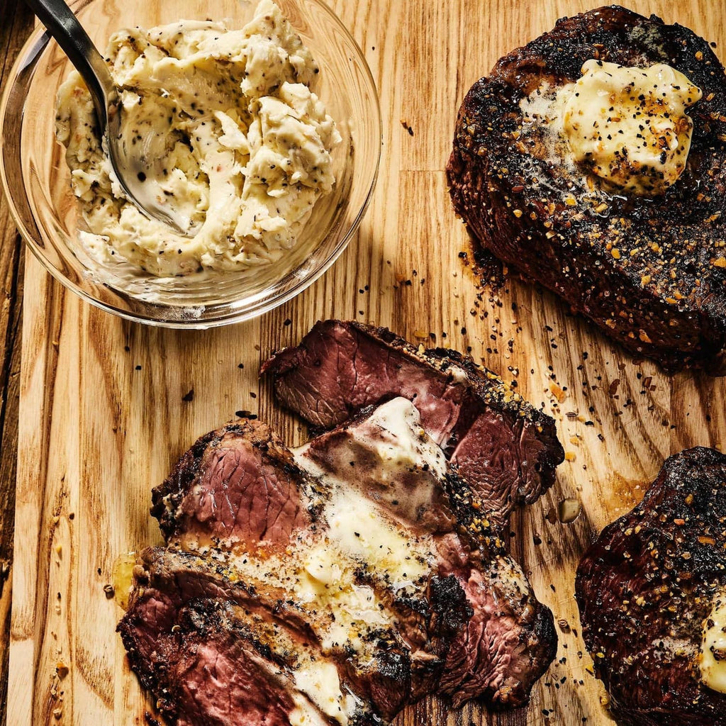 Sliced seasoned steak with creamy sauce on a wooden board