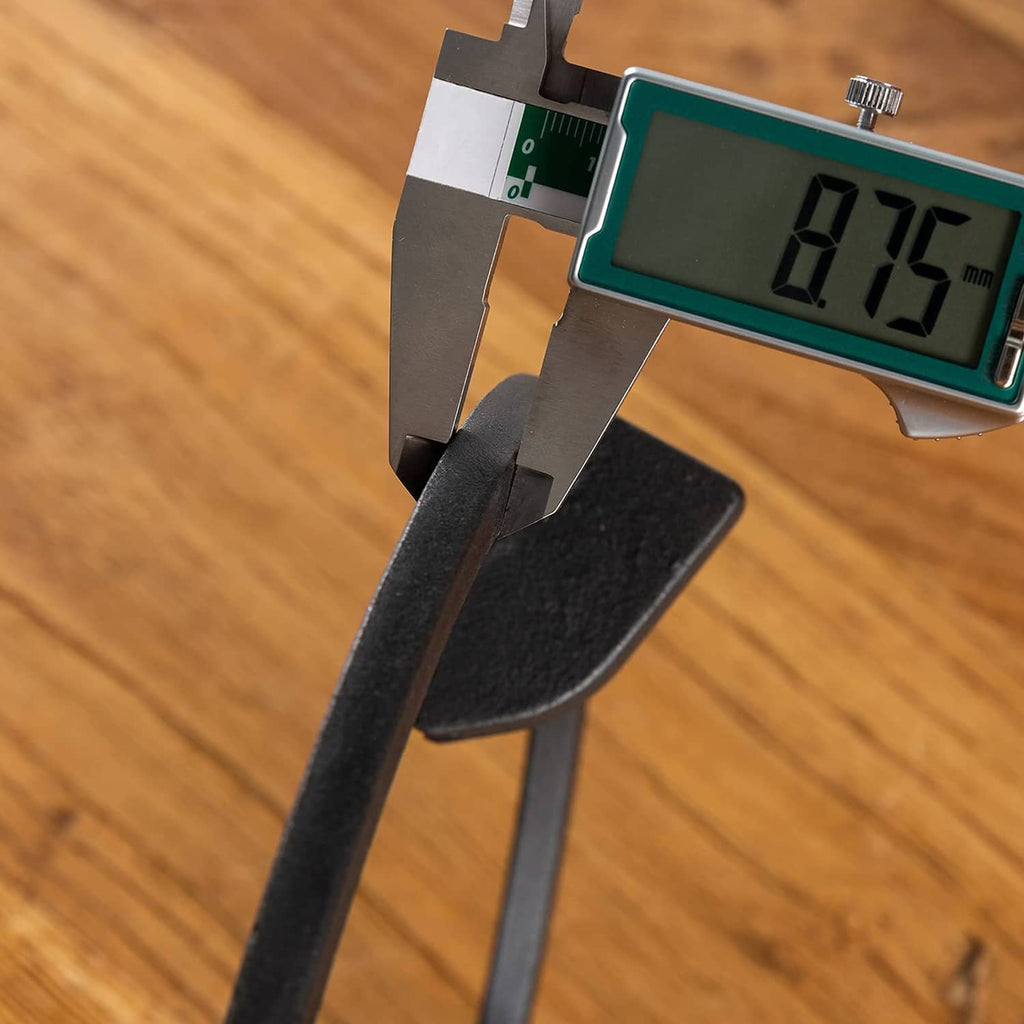 Black cast iron wok ring edge close-up with digital caliper measurement