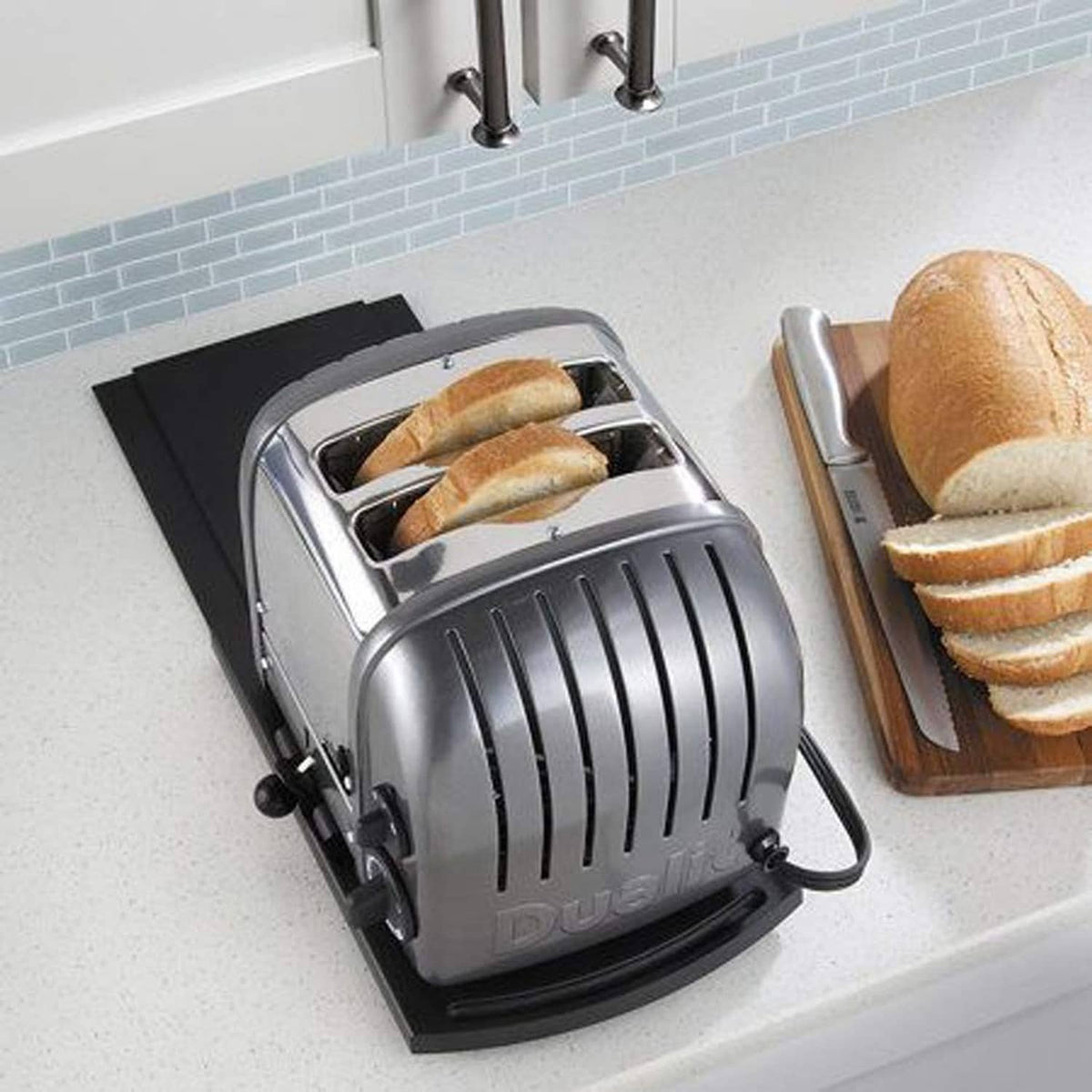 Black sliding tray mat for appliances, under a toaster on a countertop