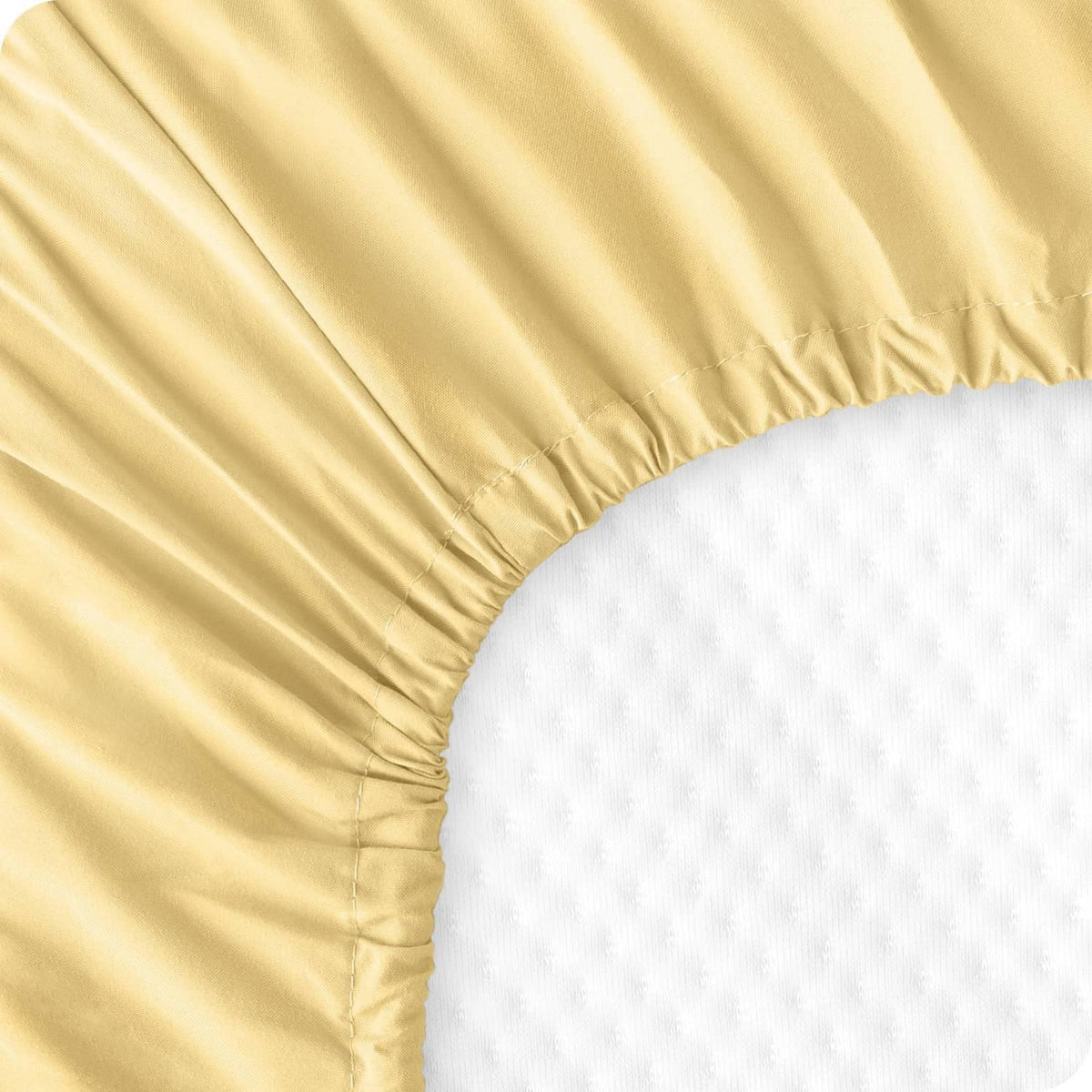 Pale yellow fitted sheet seam and elastic border detail over white fabric
