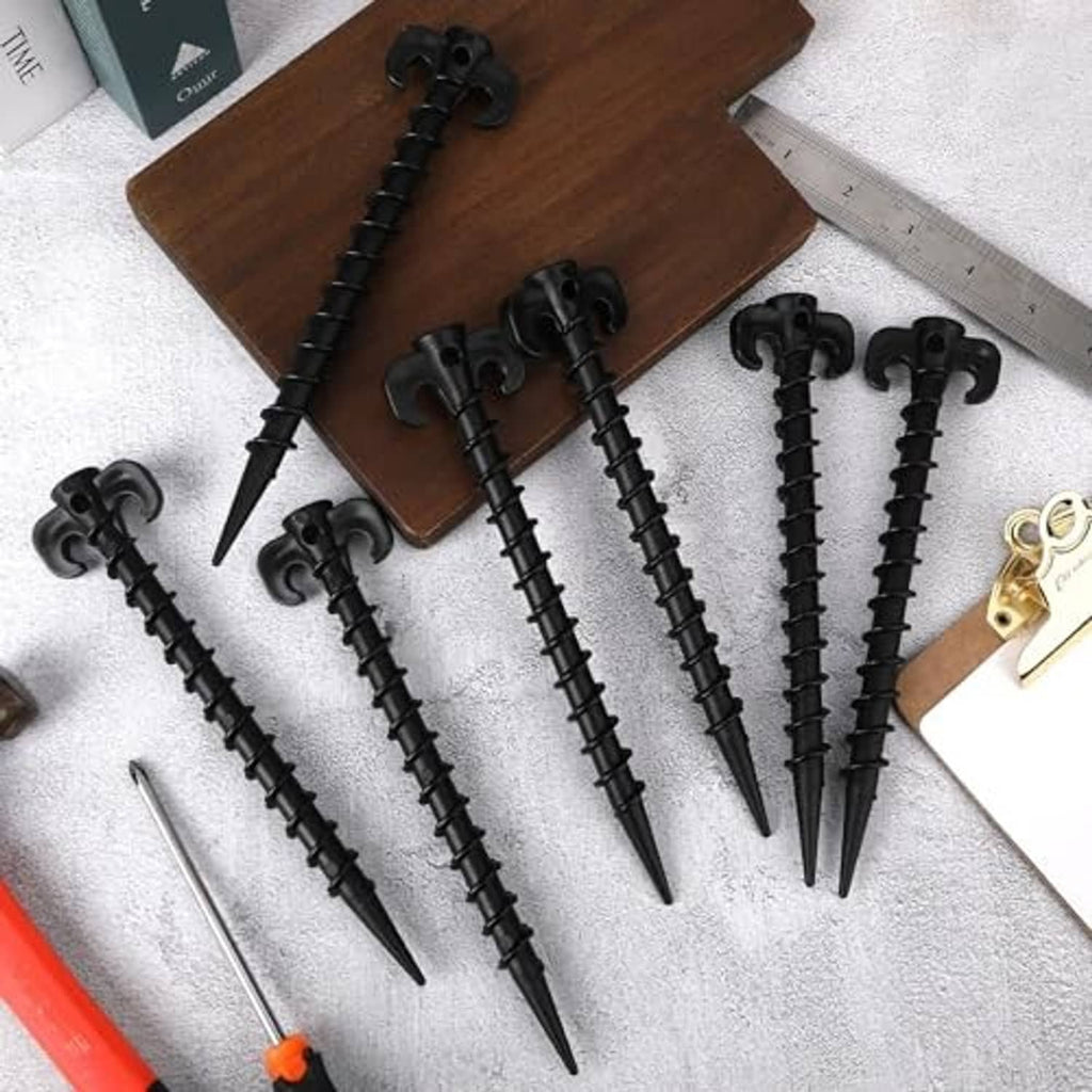 Black plastic tent stakes with C-hook heads and sharp points on a tabletop