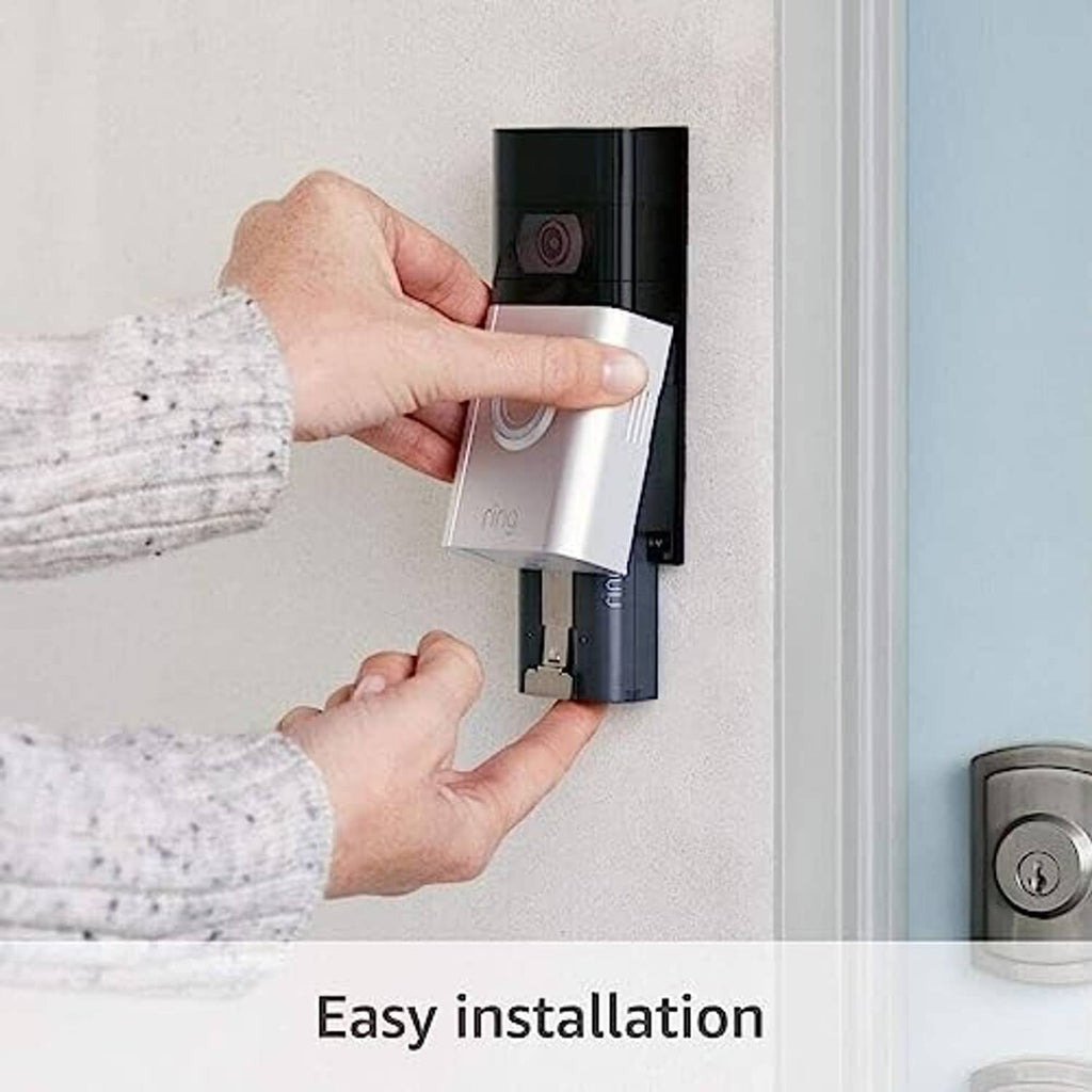 Person installing a black charging dock on a wall next to a doorbell unit