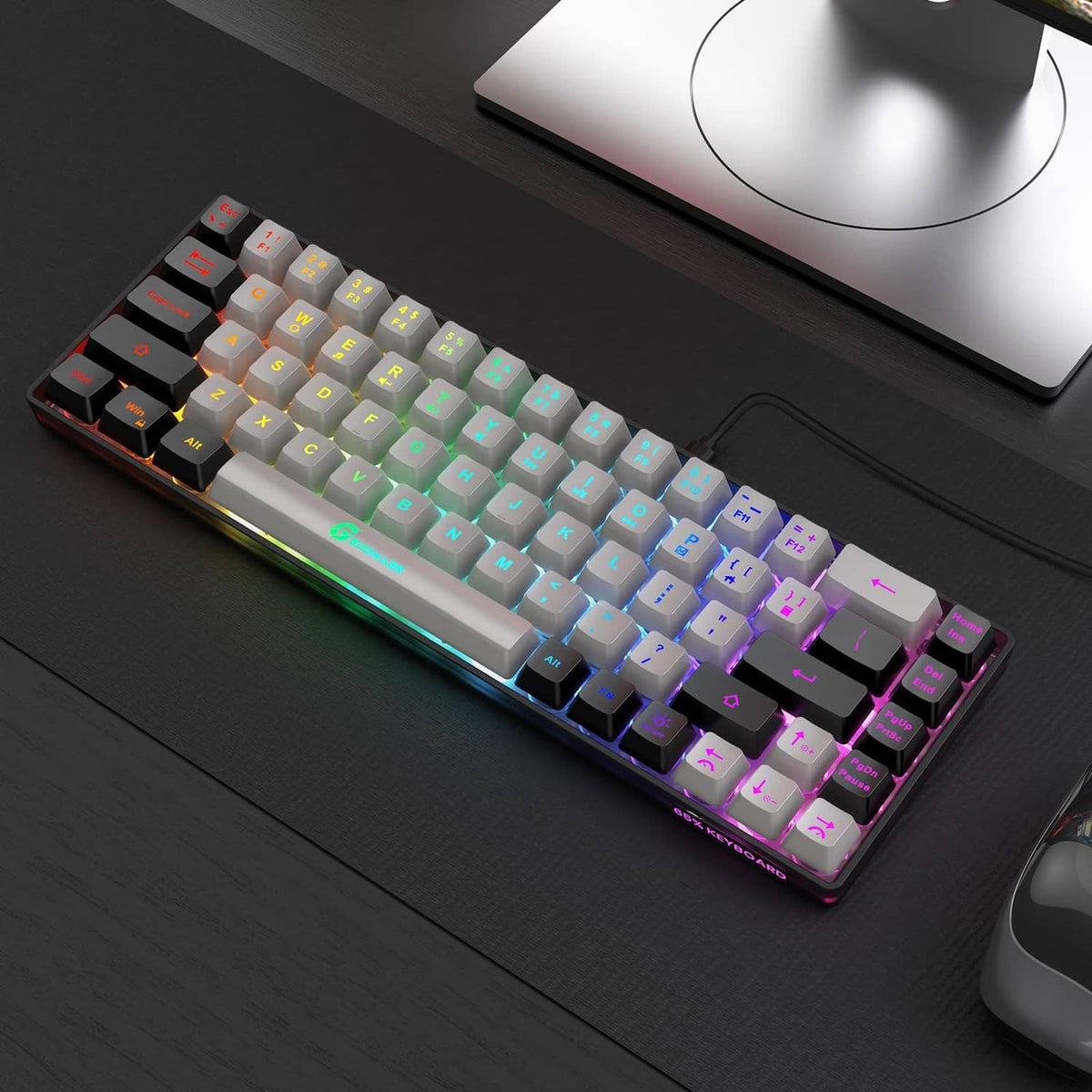 Wired mini gaming keyboard on desk, grey and black keys with rainbow RGB lighting