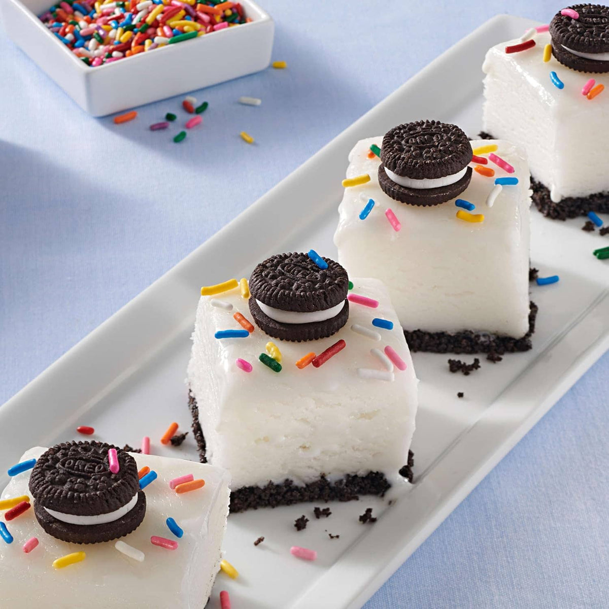 Oreo minis cookie-topped cake squares with white cream and sprinkles