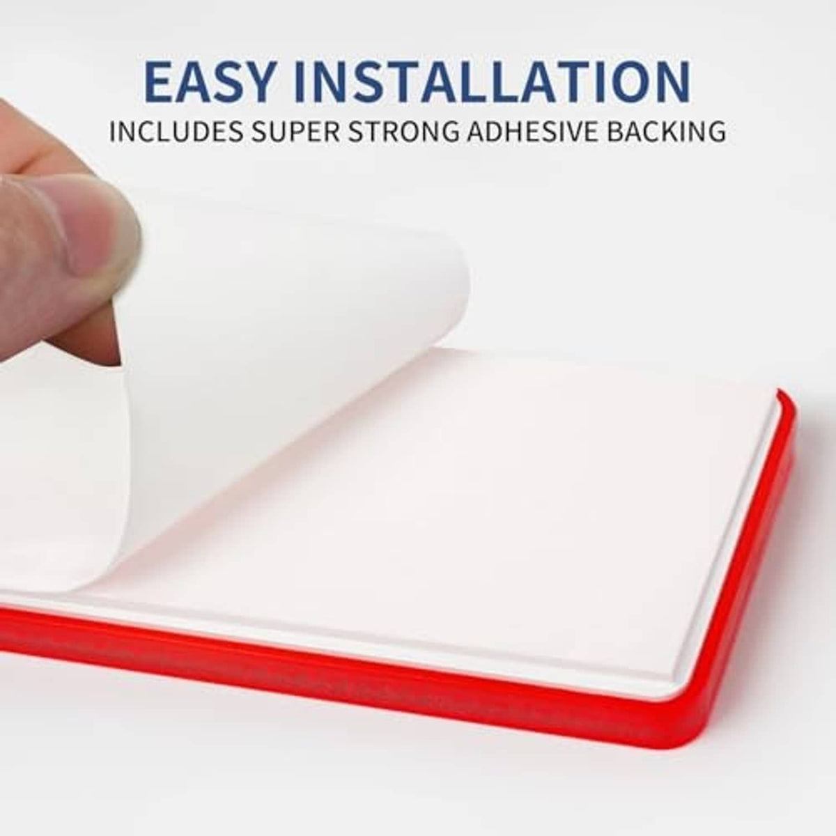 Red adhesive-backed reflector plate being pressed onto surface, glossy reflective plastic