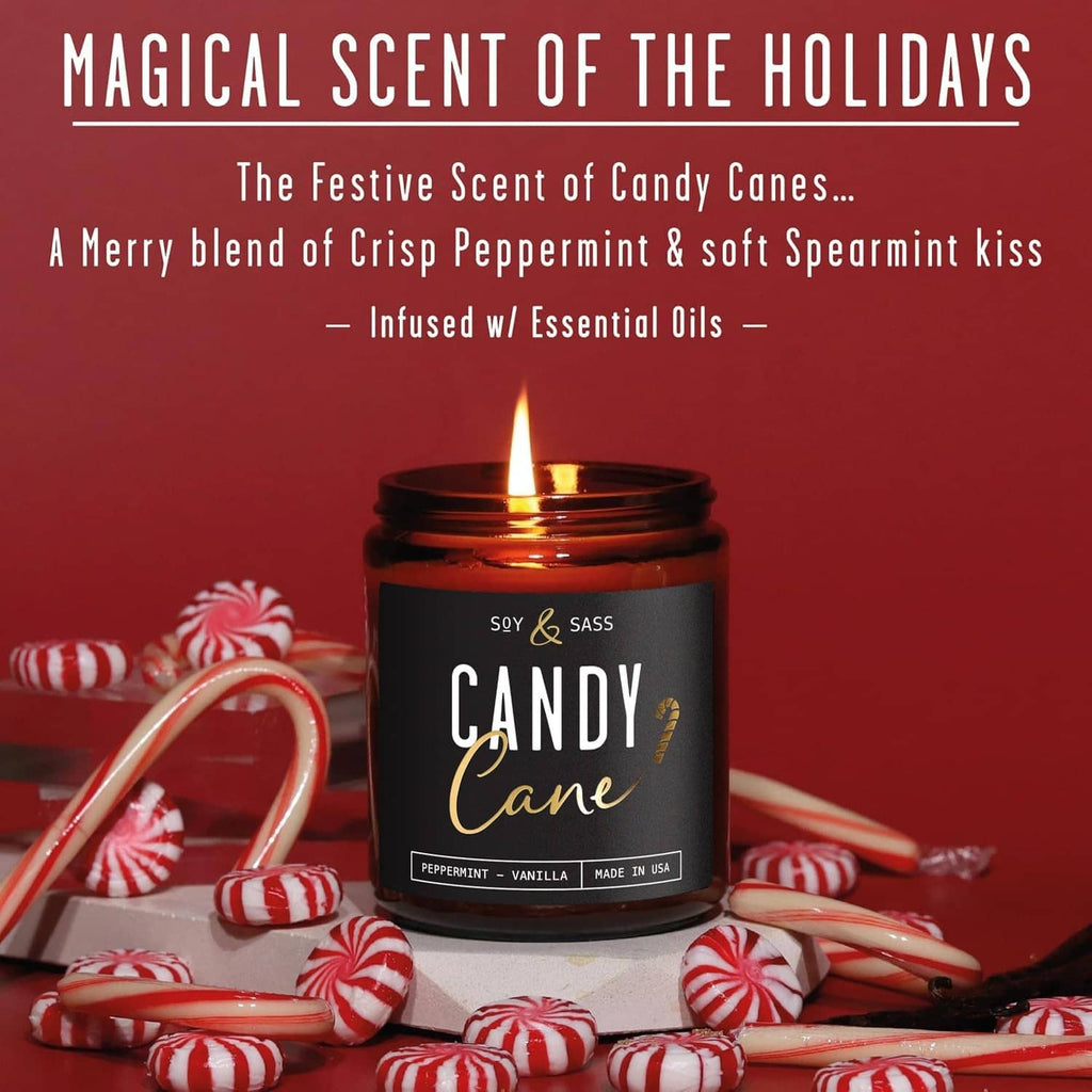 Amber glass “Candy Cane” candle jar with open flame on a table, soy & sass label