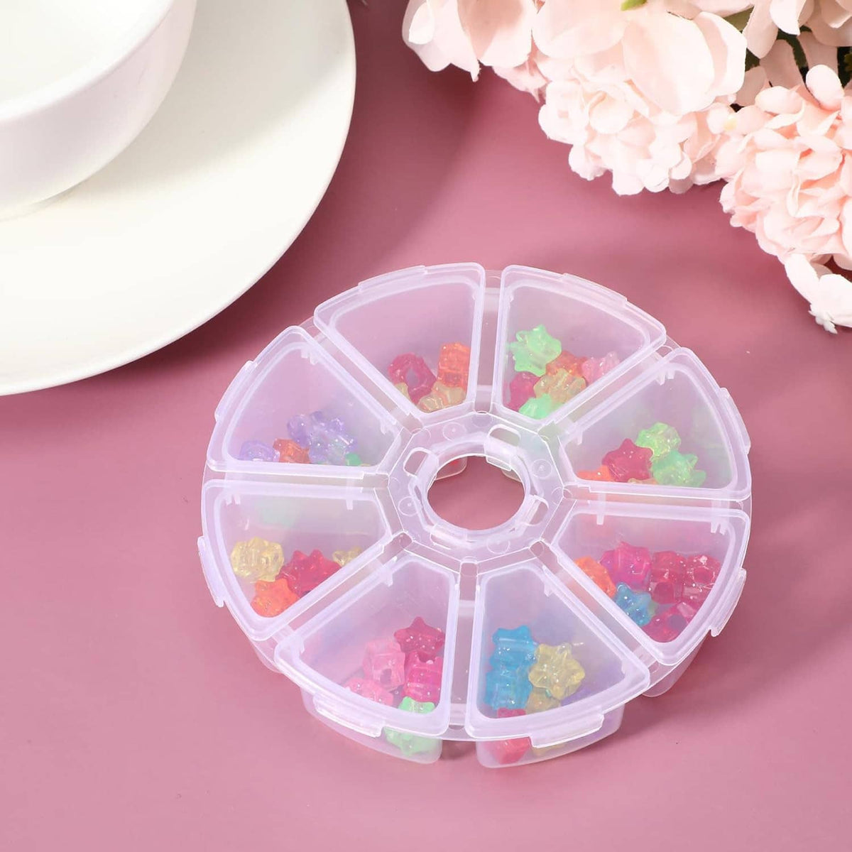 Clear round plastic bead organizer with 8 divided compartments, filled with beads