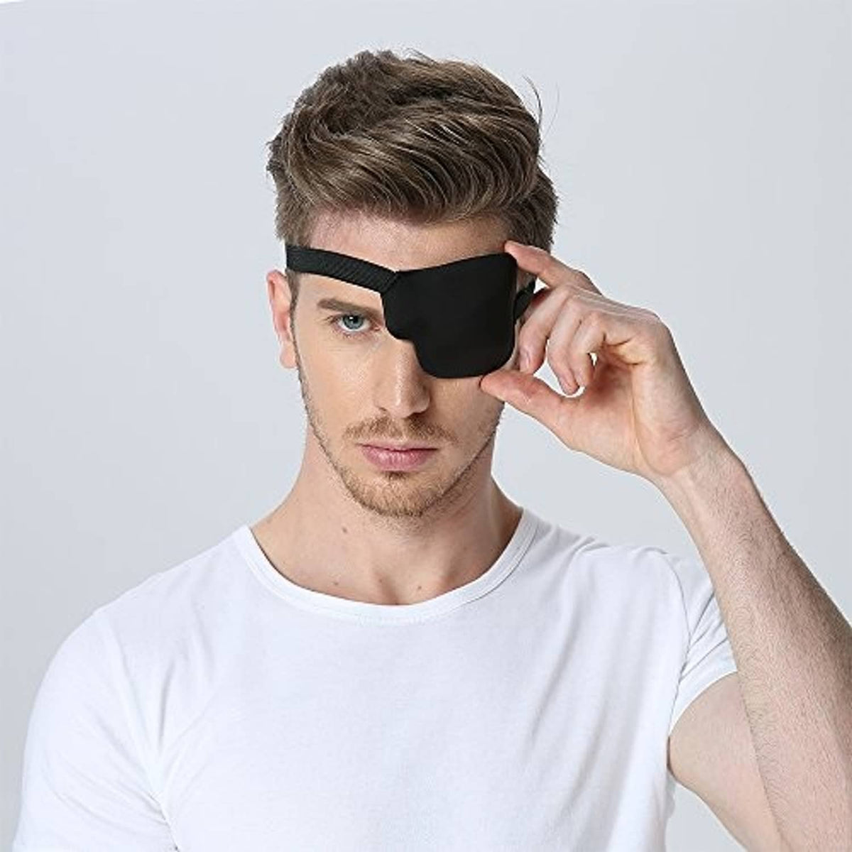 Black 3D contoured left eye patch on man, hand adjusting elastic strap