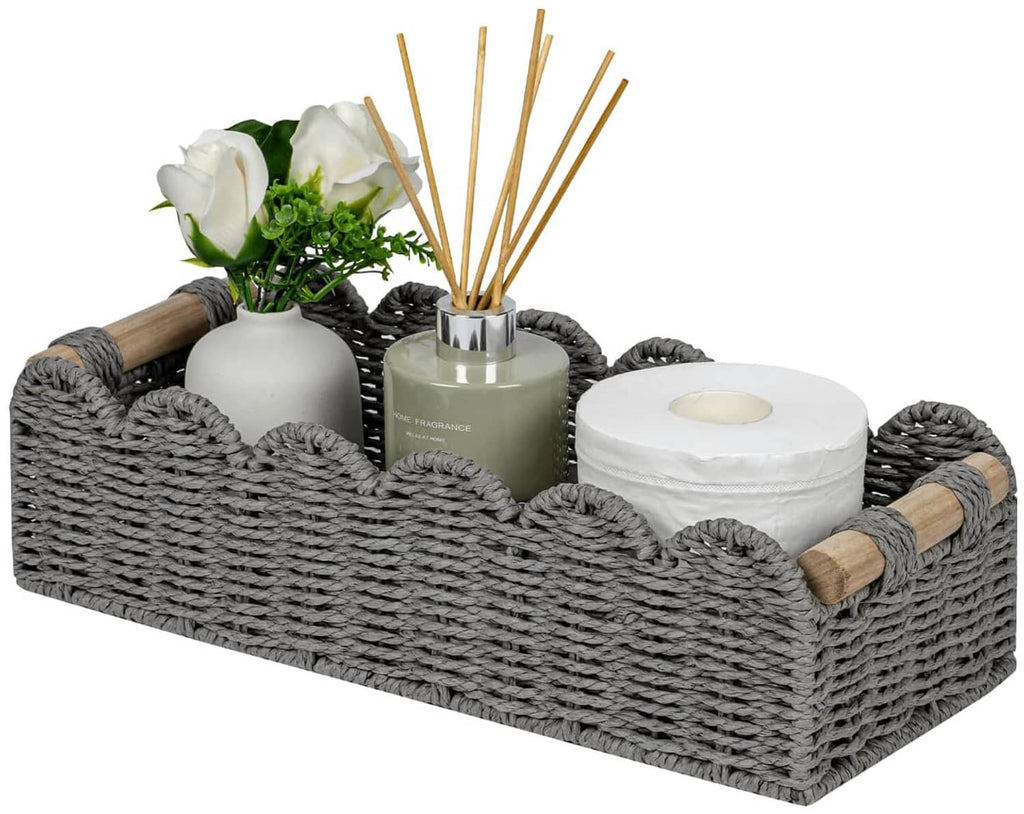 Grey woven toilet paper storage basket with scalloped top edge and small wood side handles.