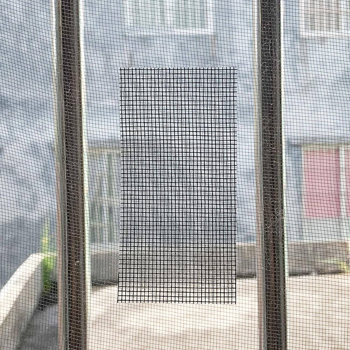 Window screen mesh patch taped over a window opening with dark grid pattern.