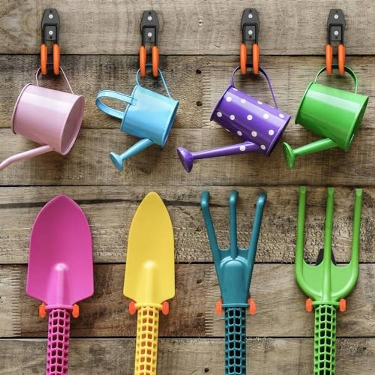 Black J-shaped hooks holding gardening tools on a wooden board