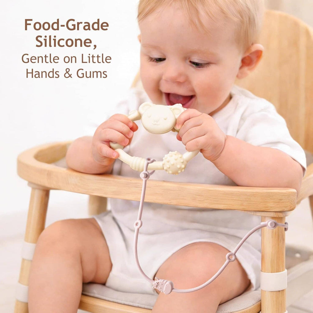 Baby in high chair with hanging silicone toy straps and teether toys attached