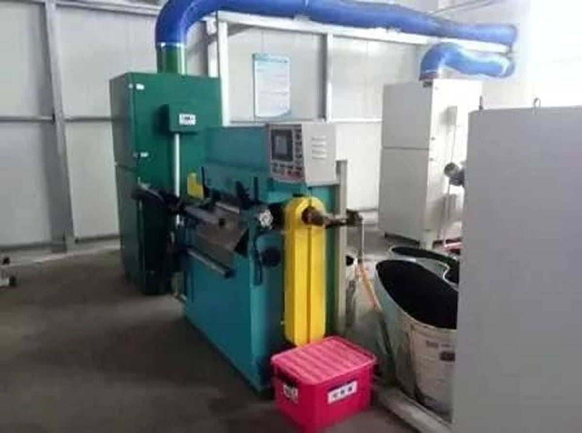 Industrial machine with green frame and yellow components in workshop