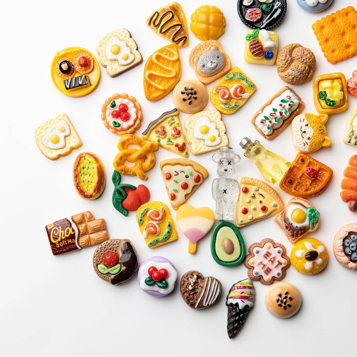 Assorted resin food charms close-up featuring mini pizza slices, cookies, hearts, and sweets