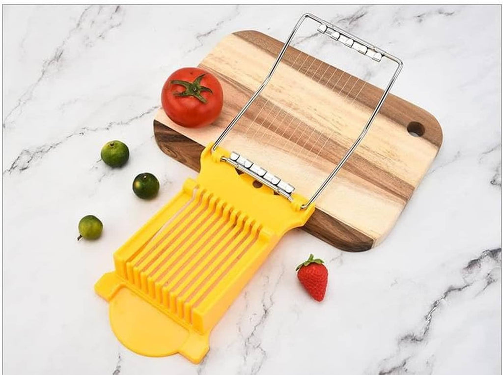 Yellow slicer with wire frame on a wooden board, next to tomatoes and limes