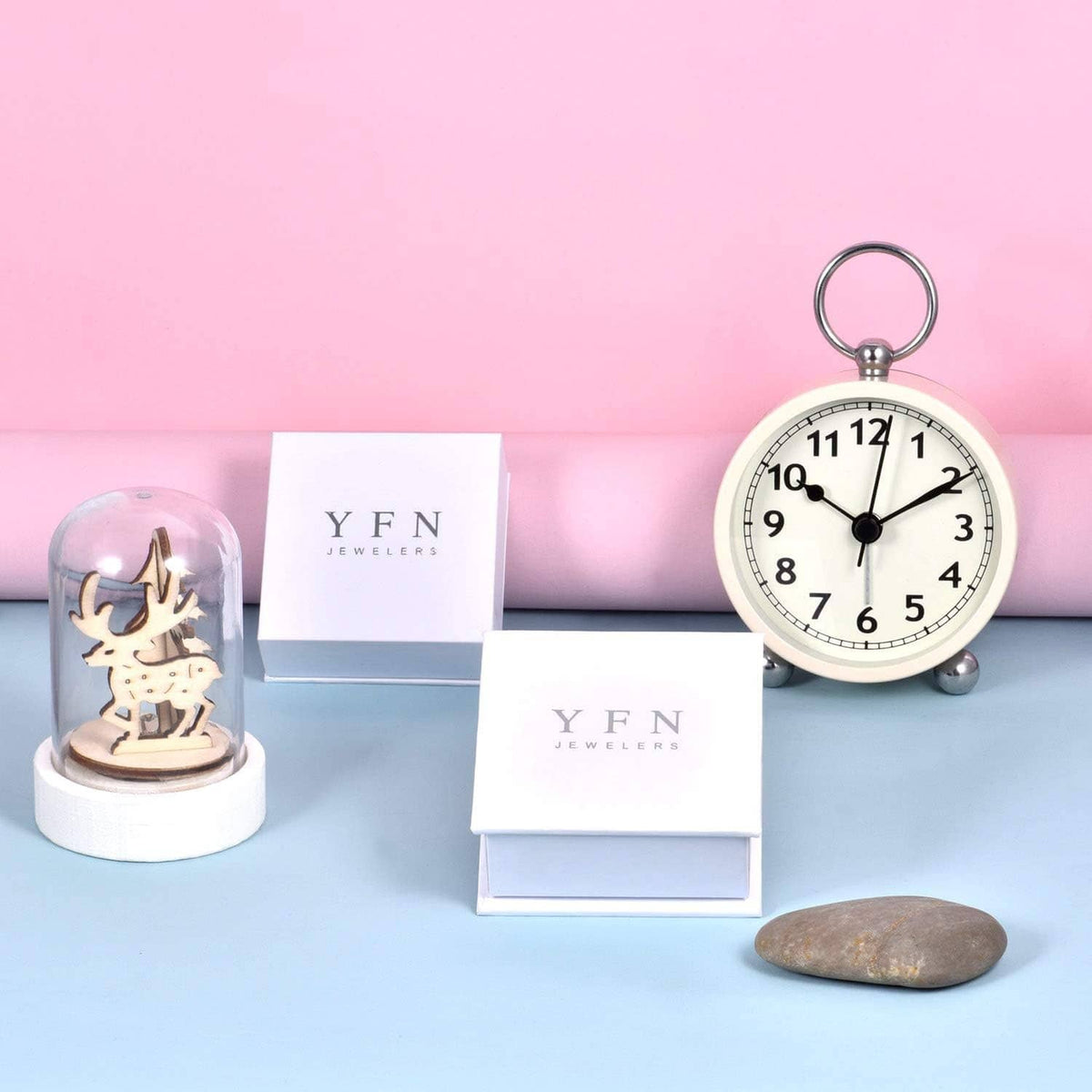 Jewelry display with branded boxes and alarm clock; necklace not visible