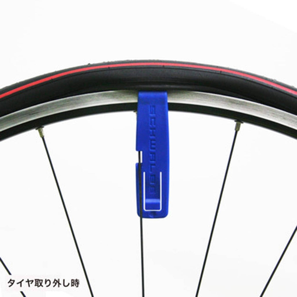 Blue tire lever attached to a bicycle rim, showing prying base on tire