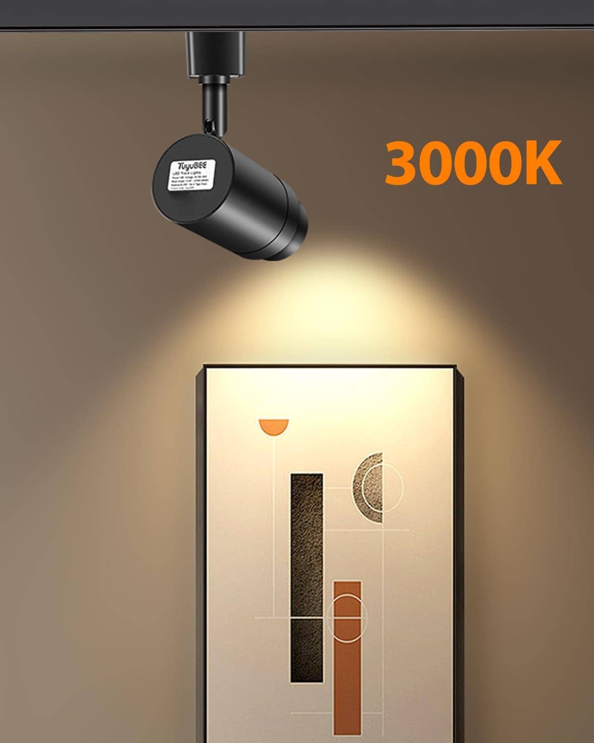 Black LED track light head projecting a warm spotlight onto wall decor