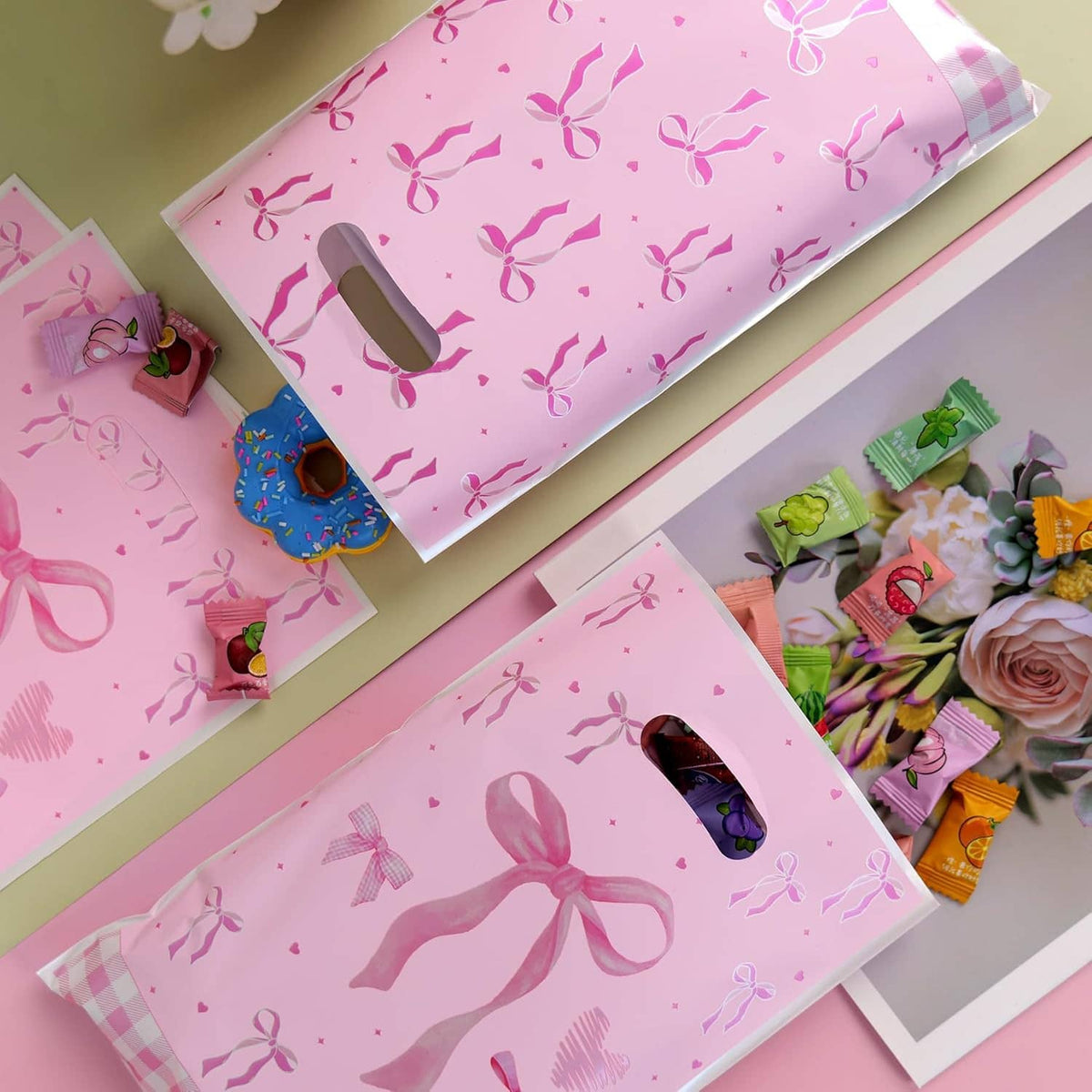 Pink bow-pattern plastic goodie bags stacked, each with a top handle cutout