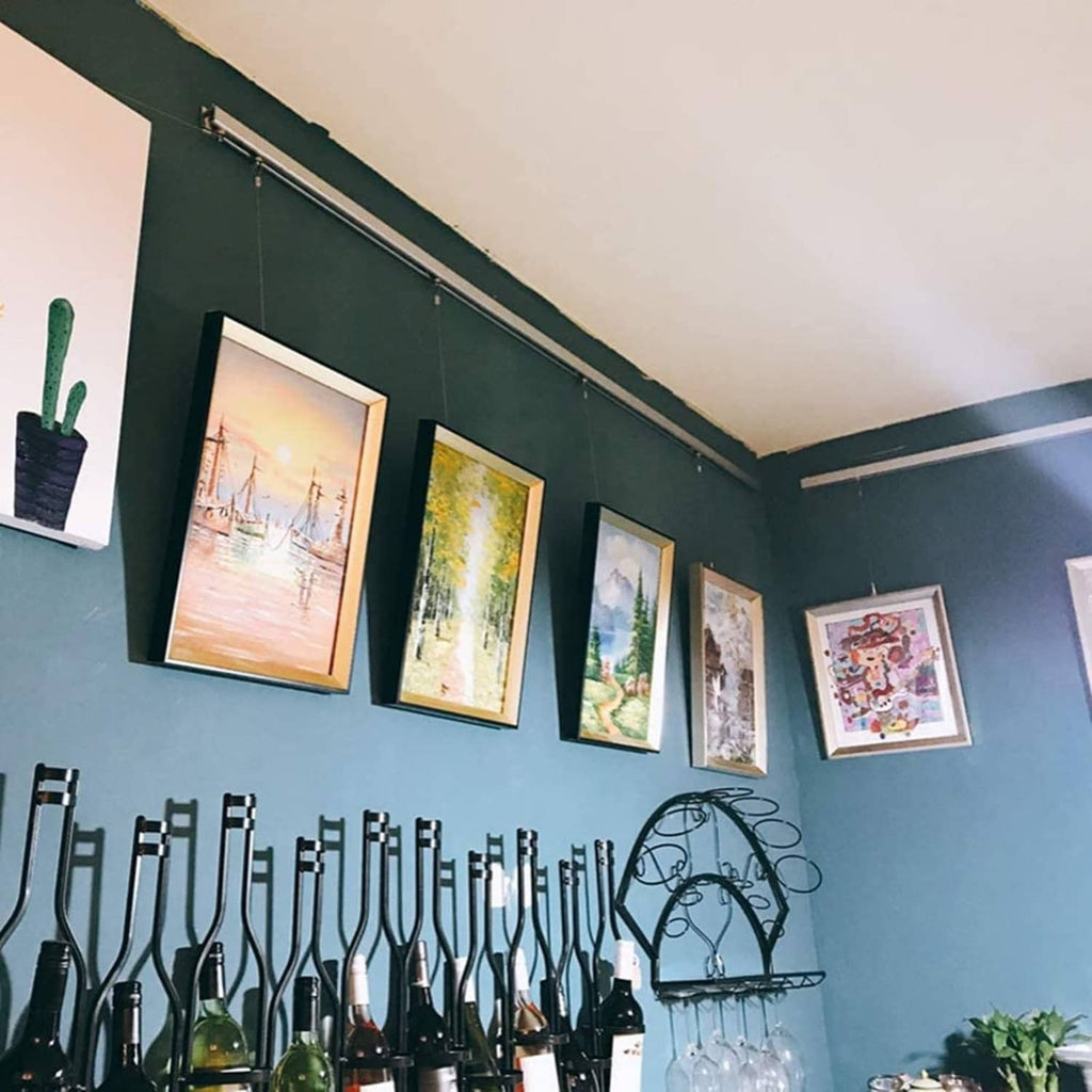 Metal gallery rope hooks holding framed art in a multi-hook wall display