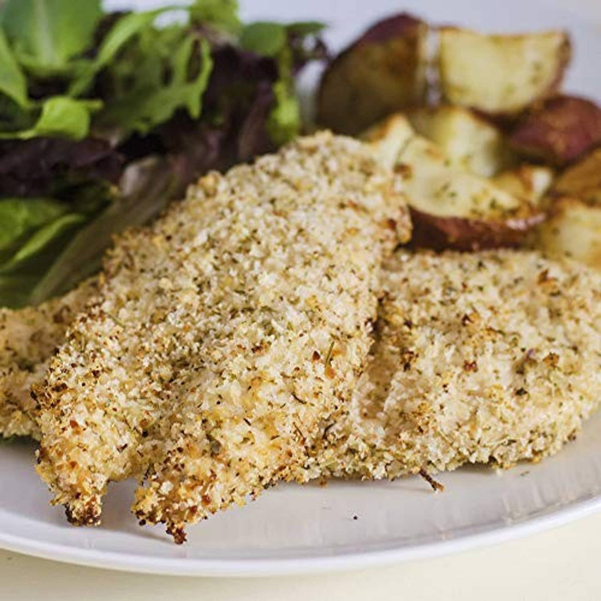 Italian herb crumb-coated chicken cutlet on a white plate