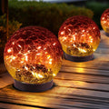Solar glass globe lights set, two gradient red glowing spheres on dark pedestal bases