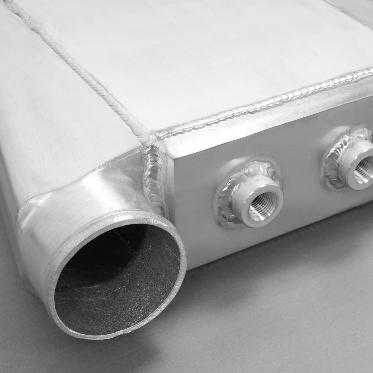 Aluminum water intercooler end tank with large tube opening and threaded fitting.