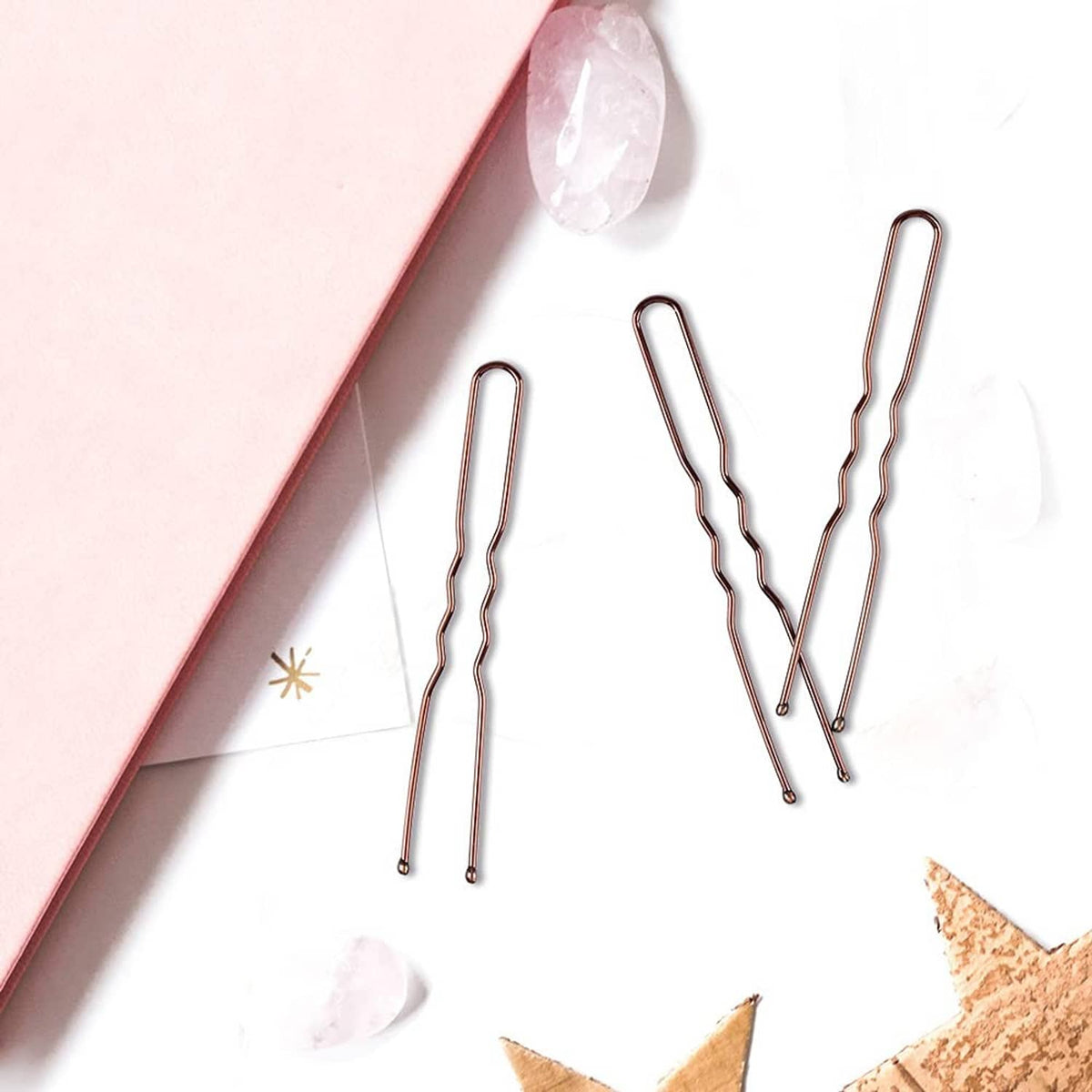 Four copper-tone U-shaped hair pins with wavy ends, arranged vertically