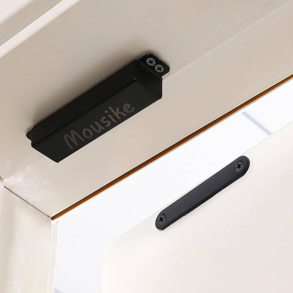 Black magnetic door catch on cabinet door with latch bar and screw heads visible