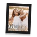 Black 8x10 picture frame holding a portrait photo of two people in a field.