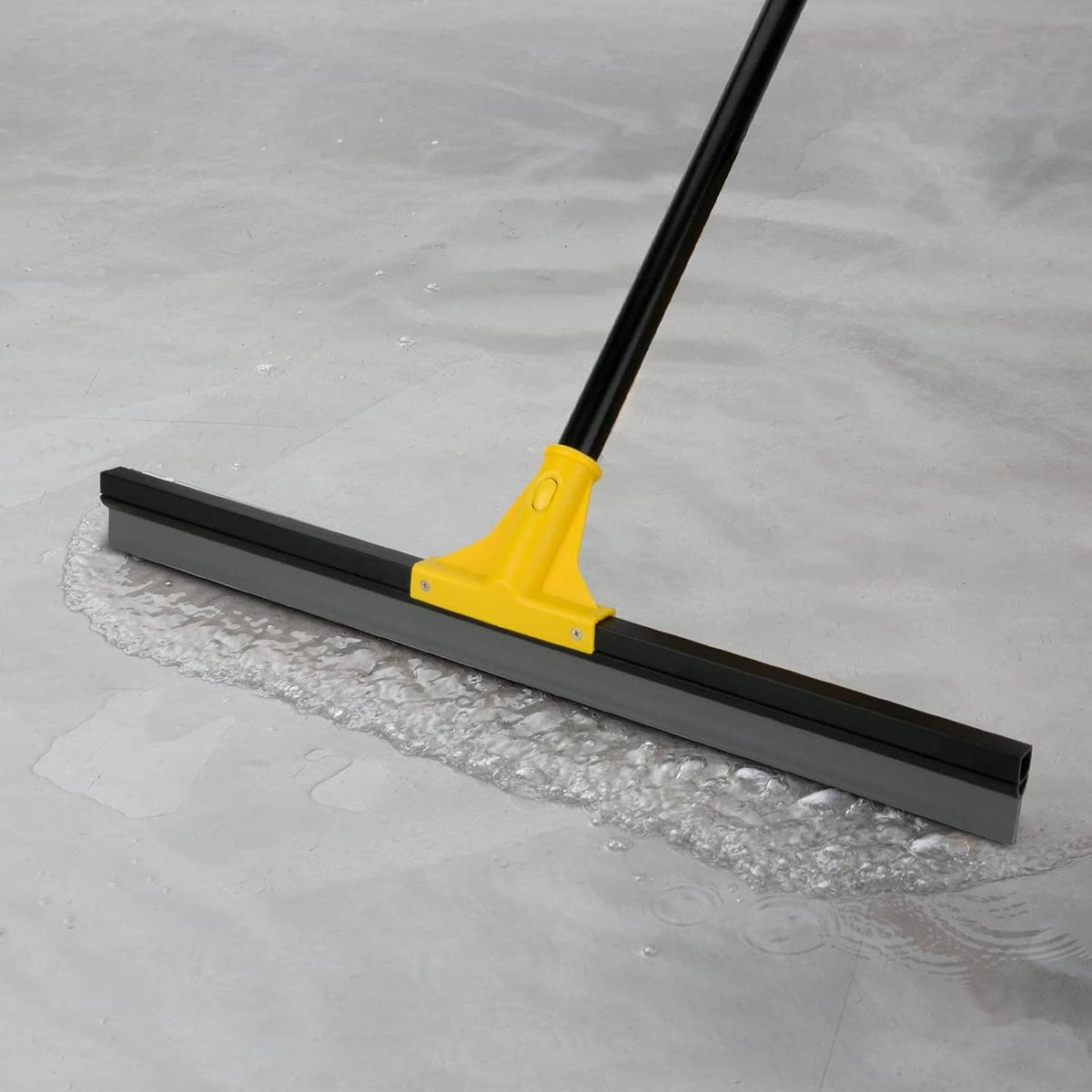 Yellow floor squeegee with black wiper blade on wet tile and concrete floor