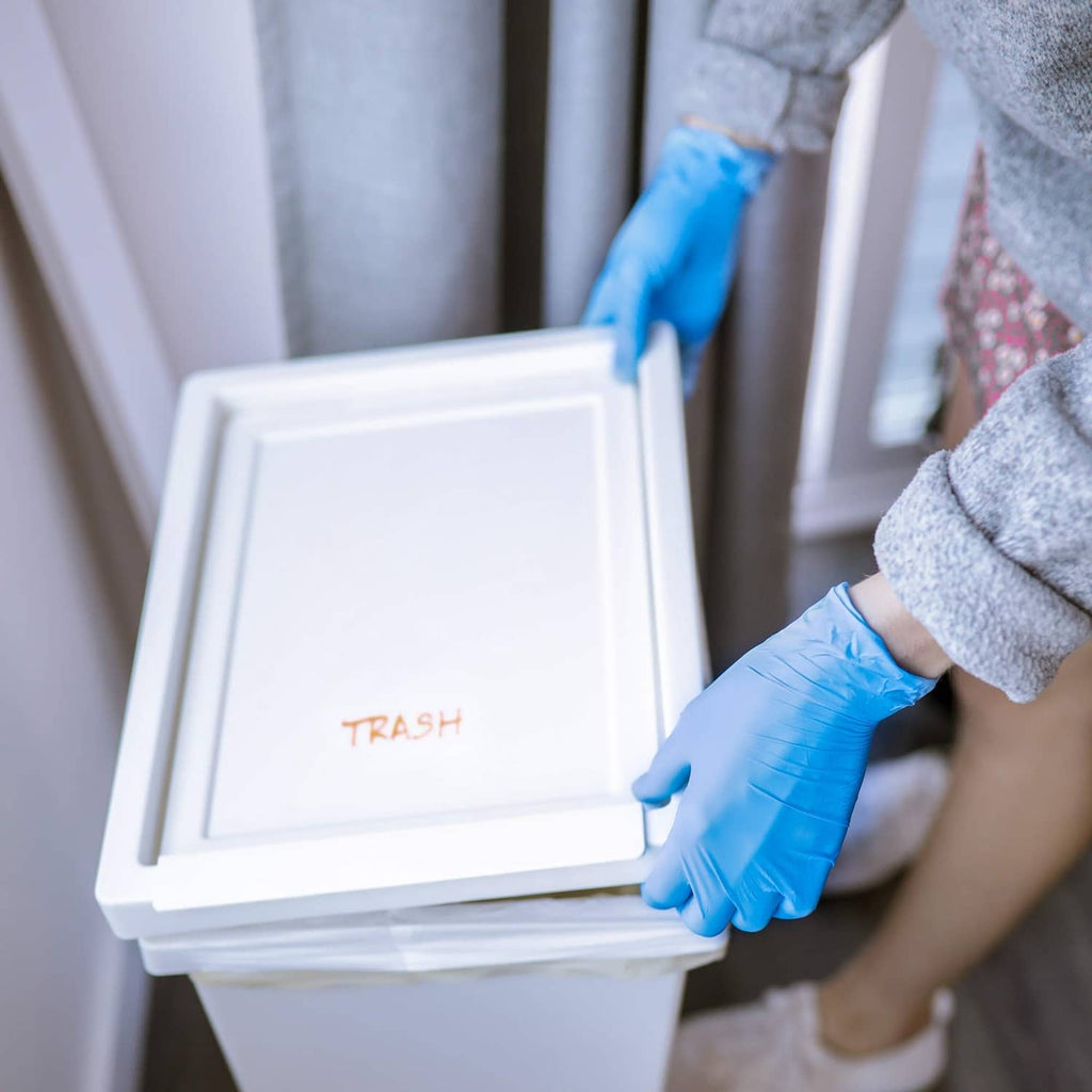 Blue nitrile glove hand placing a trash bin lid