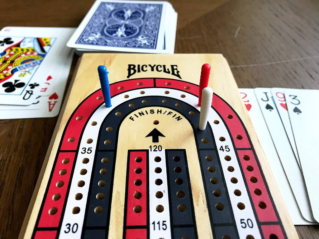 Bicycle 3-track cribbage board close-up with red and blue pegs on scoring rails