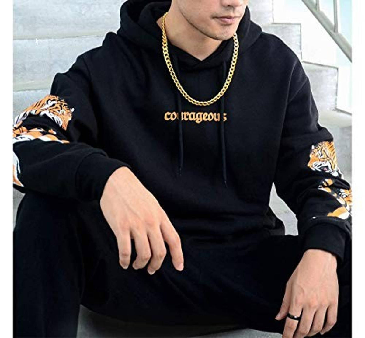 Gold chain necklace worn by a man in a dark hoodie