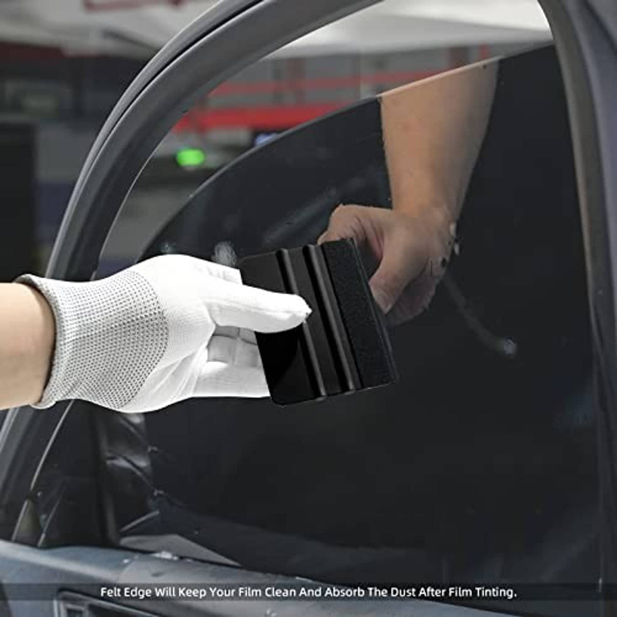 Black felt vinyl squeegee smoothing window glass film with gloved hand