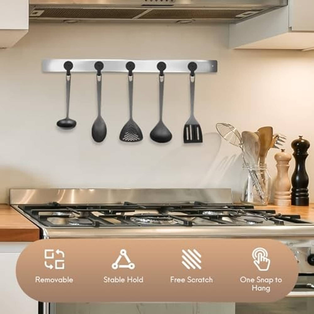 Black magnetic hooks holding kitchen utensils on a metal rail