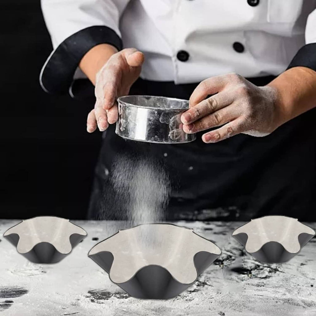 Chef uses a metal ring tool to remove food from a black nonstick taco mold