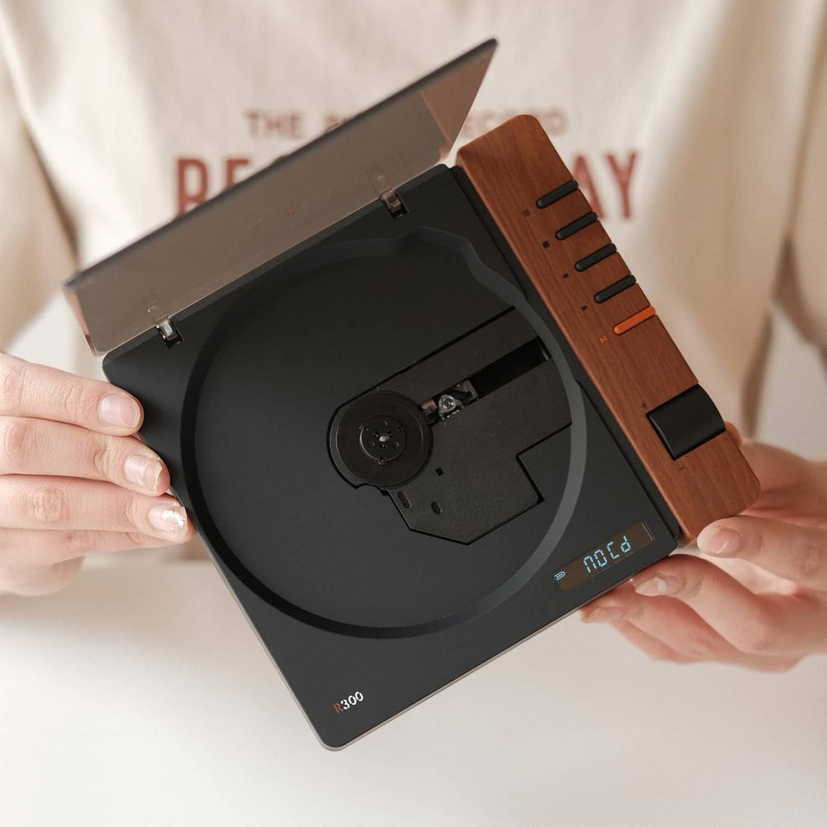 Portable retro CD player open, showing disc spindle and wood side with buttons