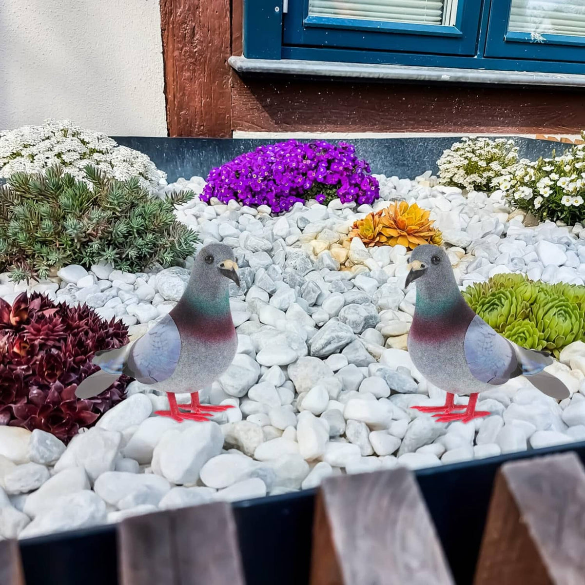 Two foam pigeon bird figurines with gray bodies and red feet on white gravel