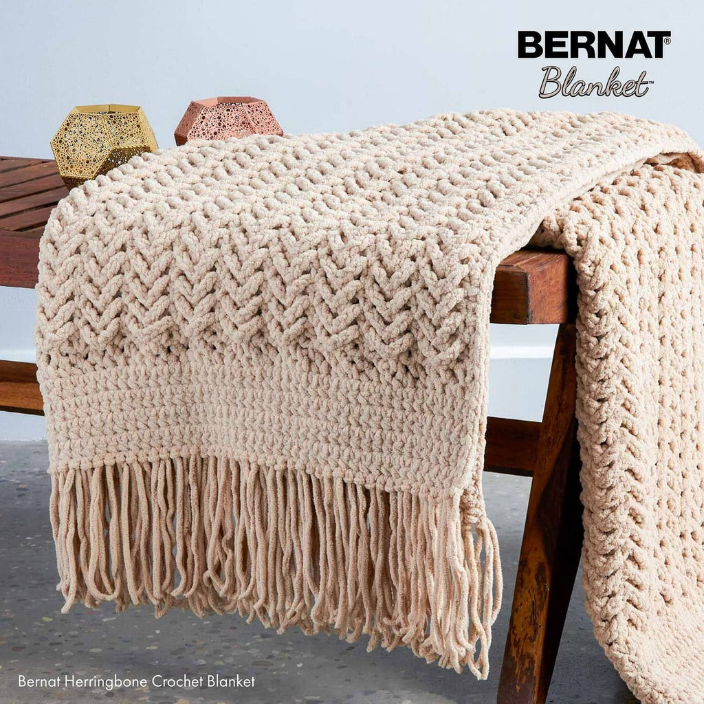 Chunky cream crochet blanket with textured herringbone stitch and long fringe