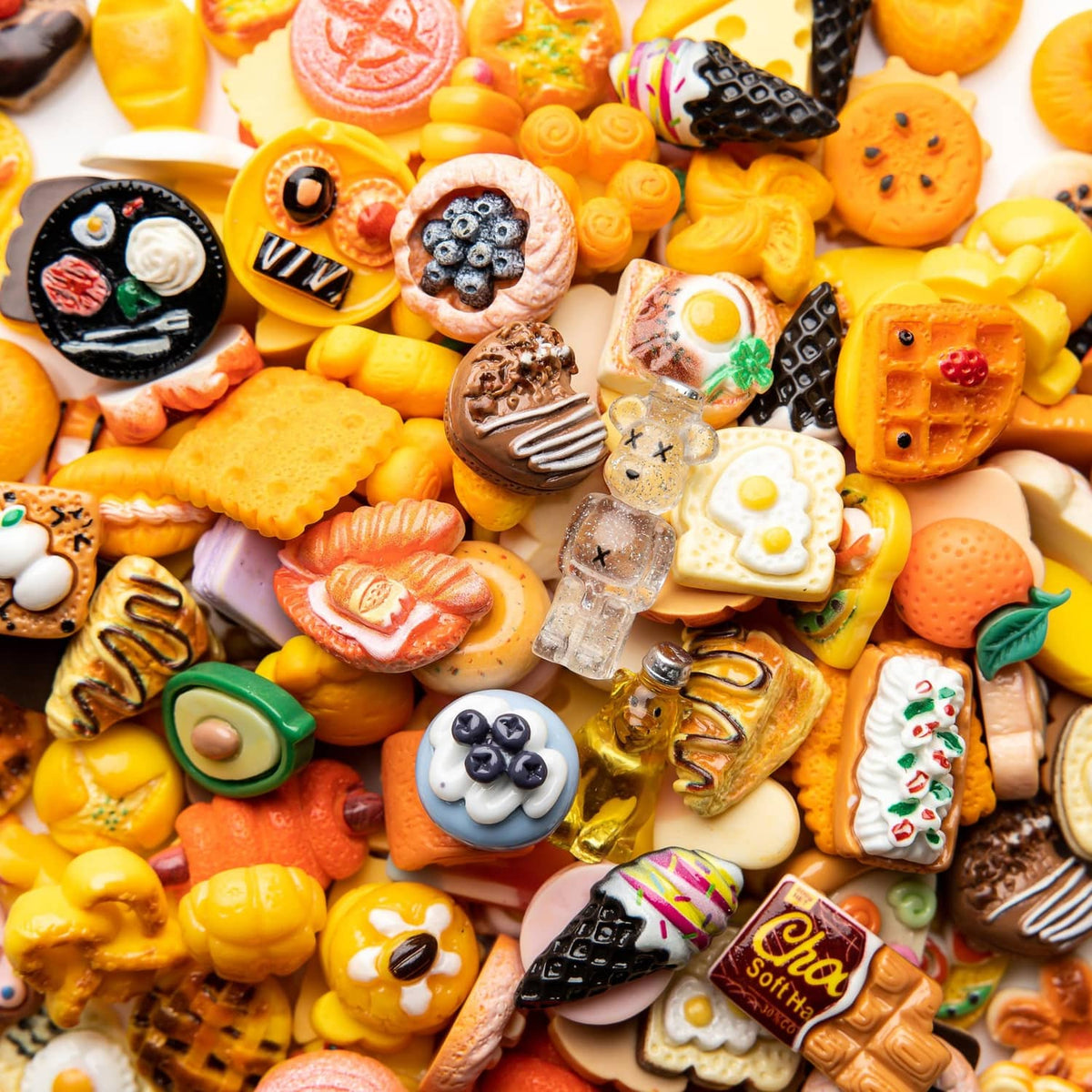 Close-up assorted resin food charms with bright pastries, cookies, pizza, and drink miniatures