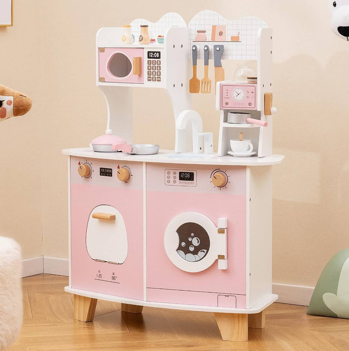 Pink and white wooden play kitchen set with sink, stove, oven door, and coffee maker