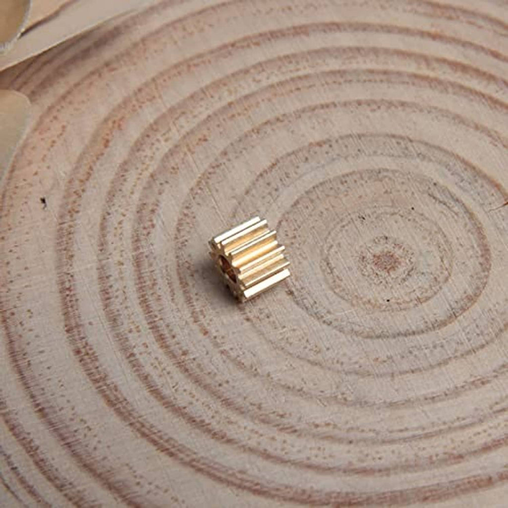 Brass 12-tooth spur gear with 3 mm bore, shown on a wooden slice