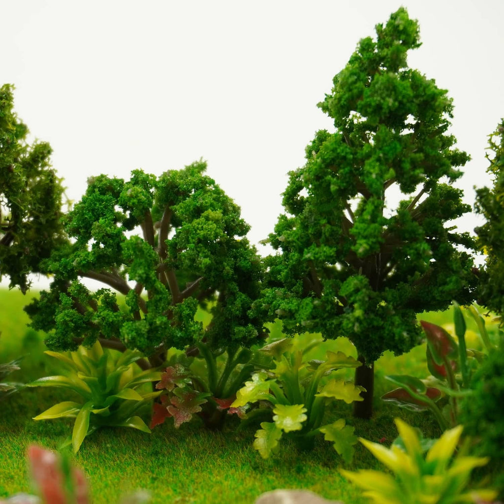 Tall leafy green model trees with layered miniature foliage and grass