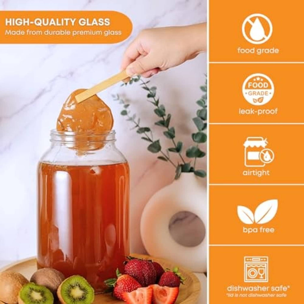 Large clear wide-mouth glass jar with airlock lid, filled with amber liquid